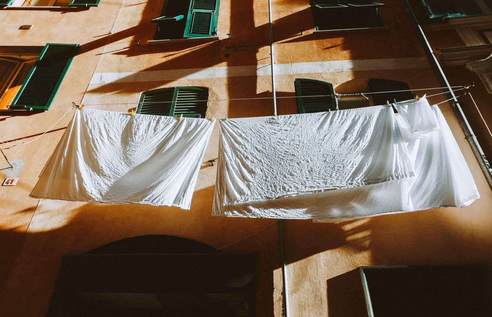 White linens hanging on sunlit clotheslines between buildings