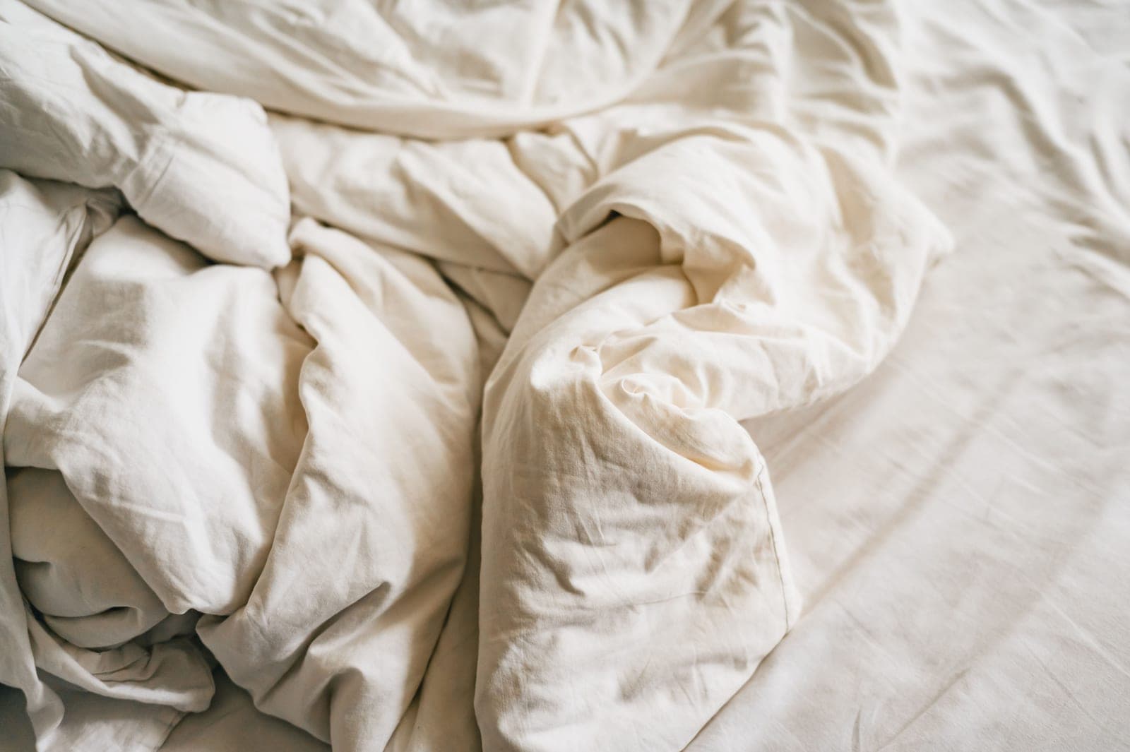 A thick folded comforter and blankets stacked on a bed