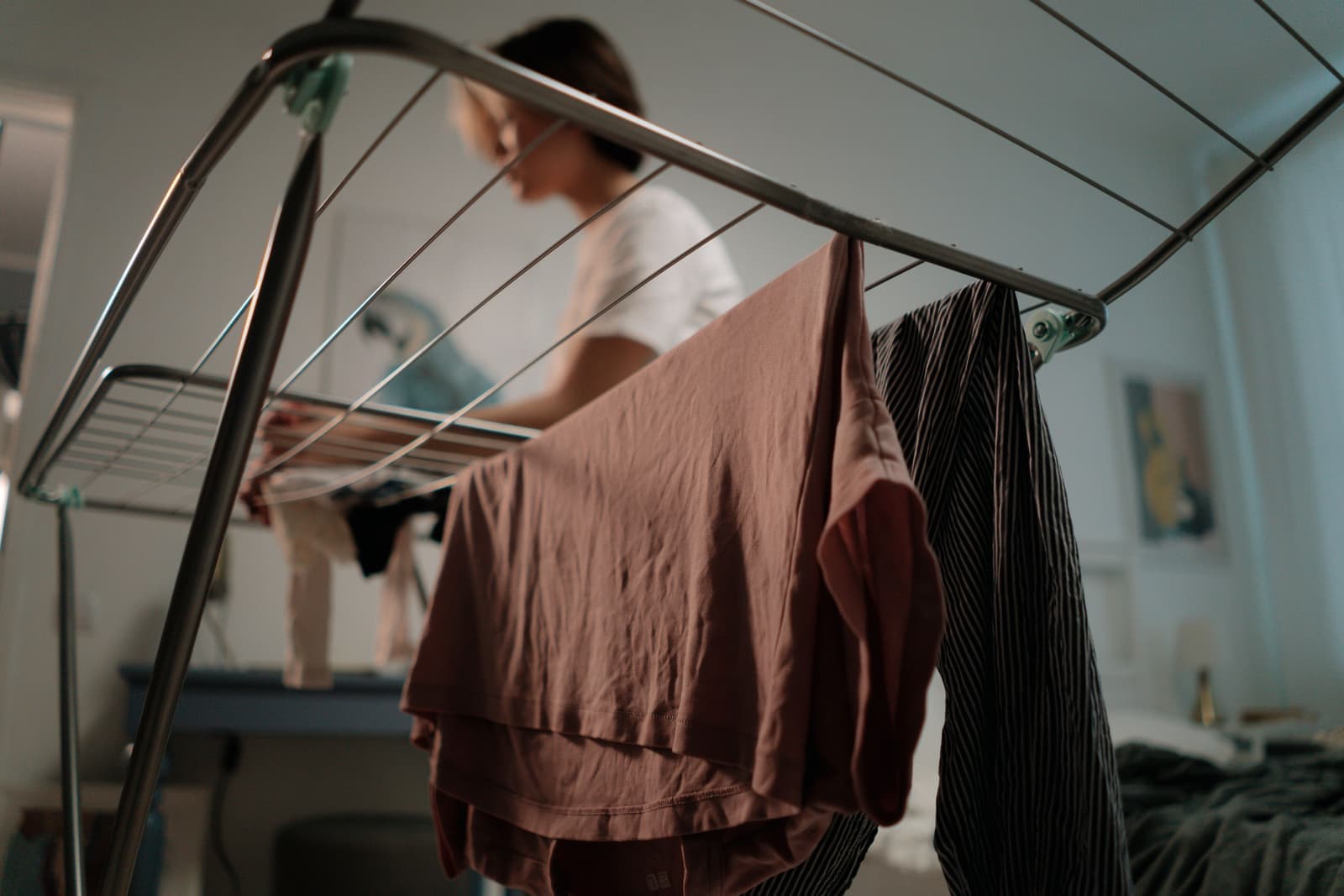 A person hanging freshly washed clothes on a drying rack at home