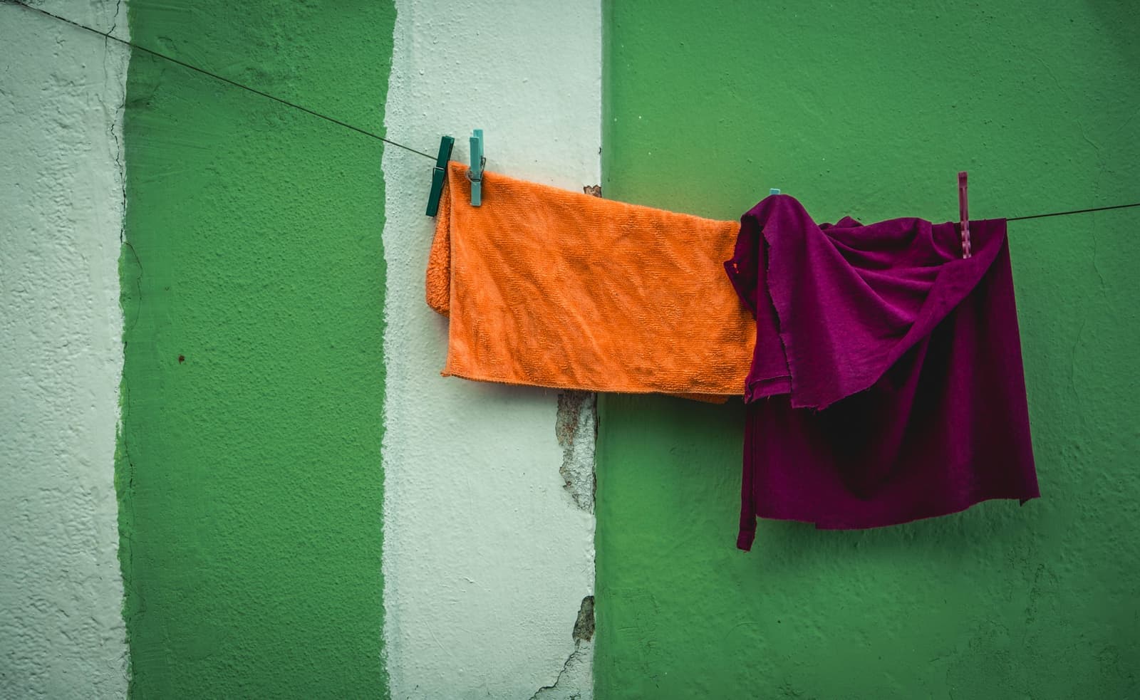 Towels pegged to a clothesline against a painted wall