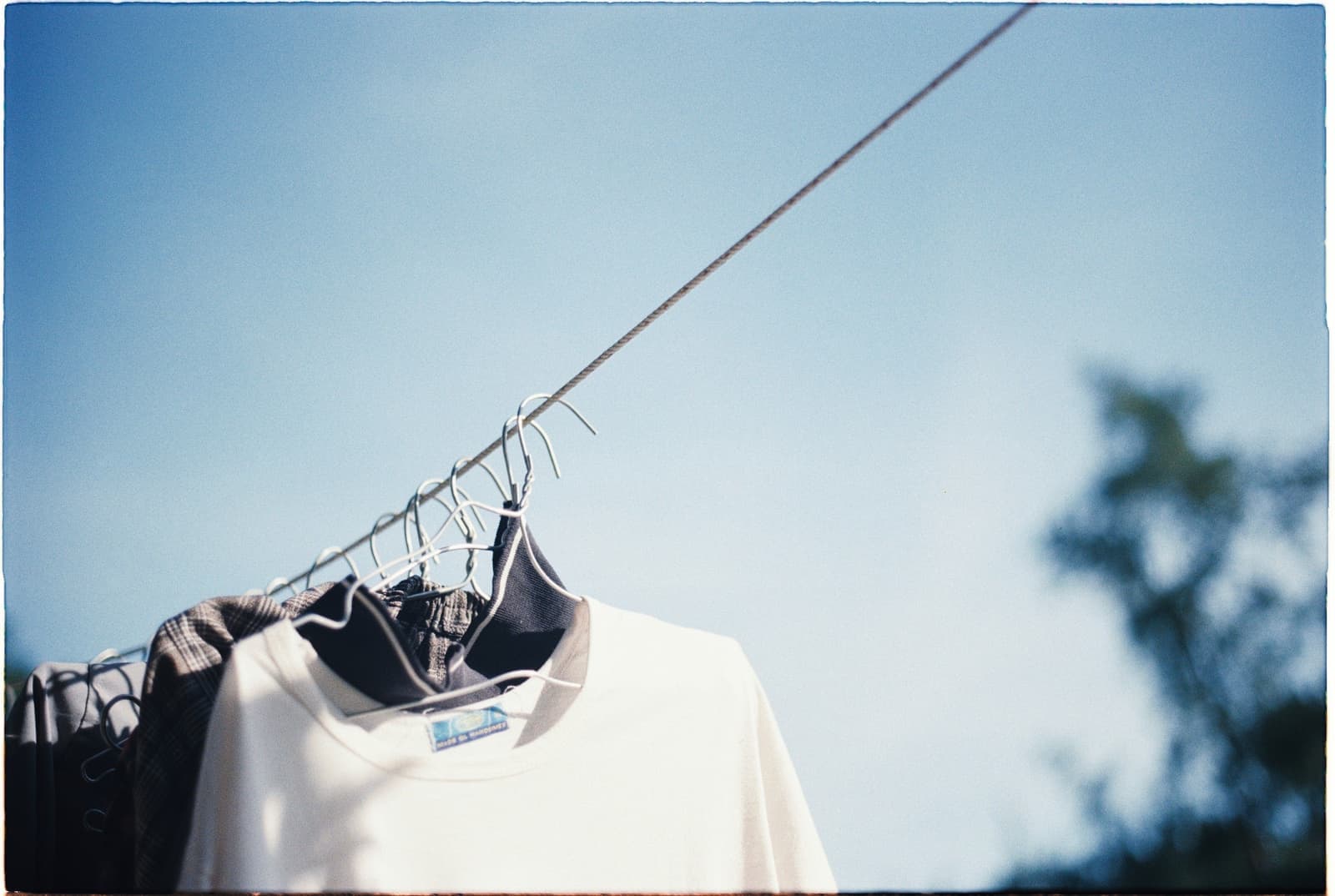 Laundry hanging outdoors on hangers under a clear sky