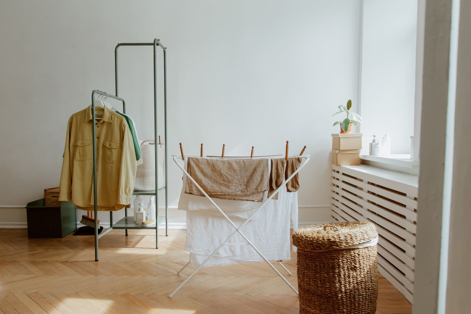 A tall slim drying rack holding laundry in a bright room
