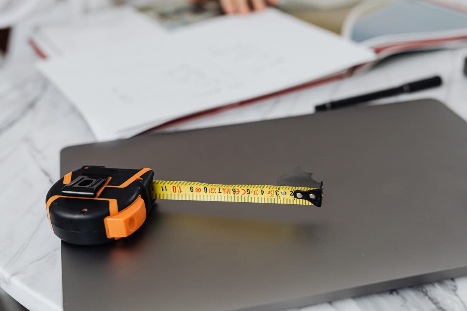 A tape measure and a notebook on a desk