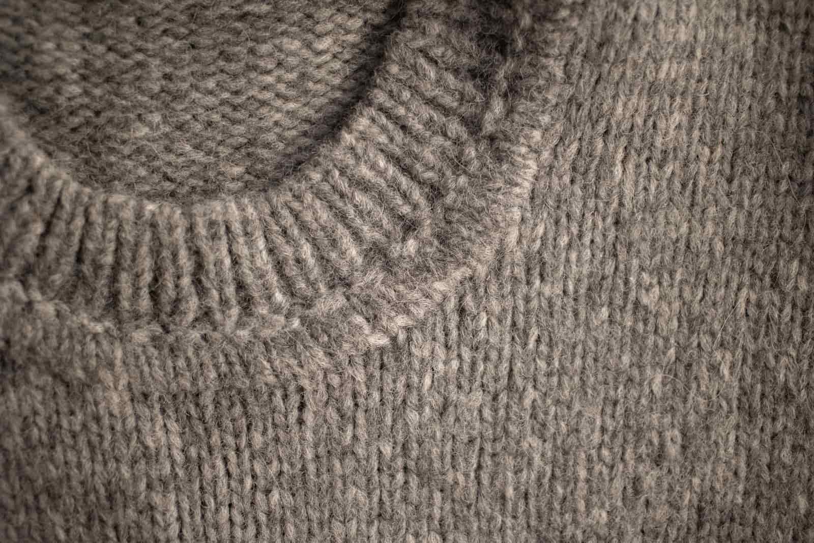 A knitted wool sweater laid flat on a pale surface