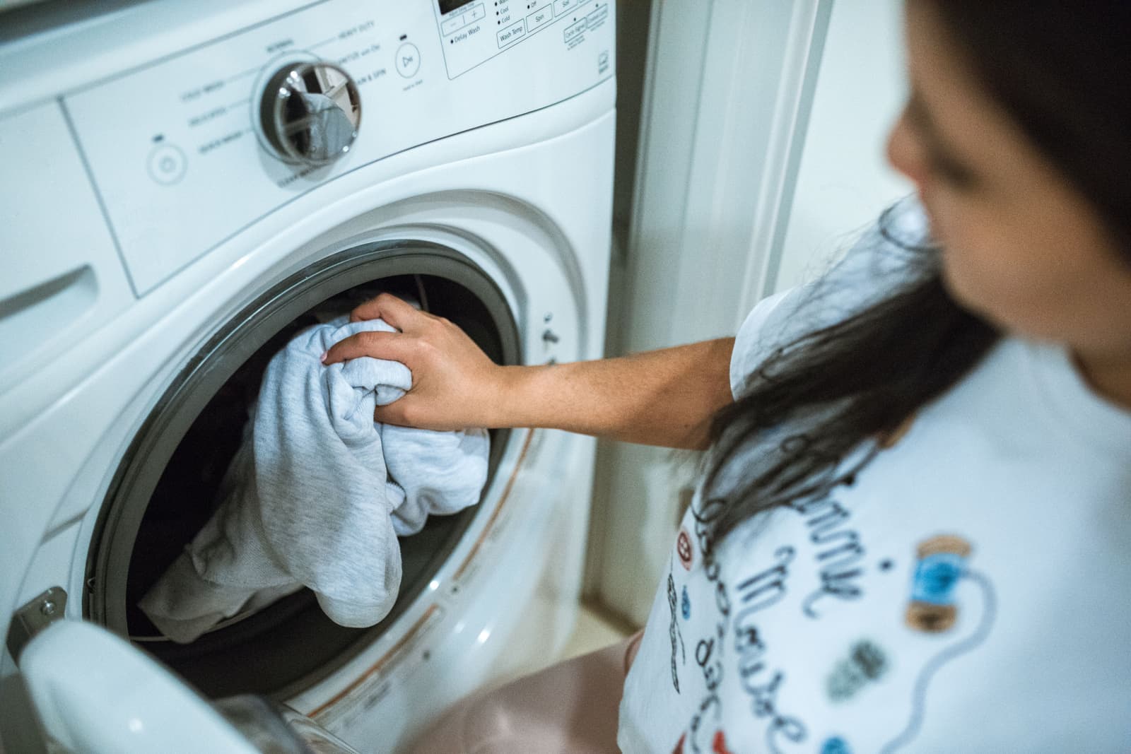 A person loading laundry into a compact machine indoors
