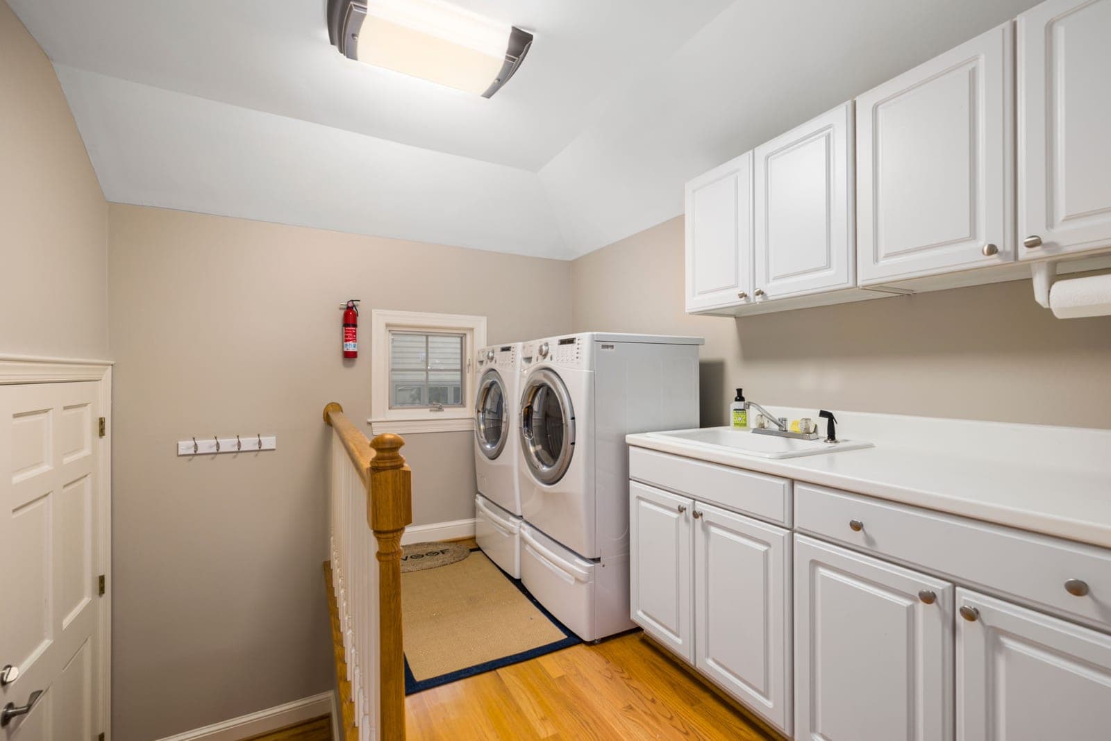 A bright laundry room with a washer and white cabinets