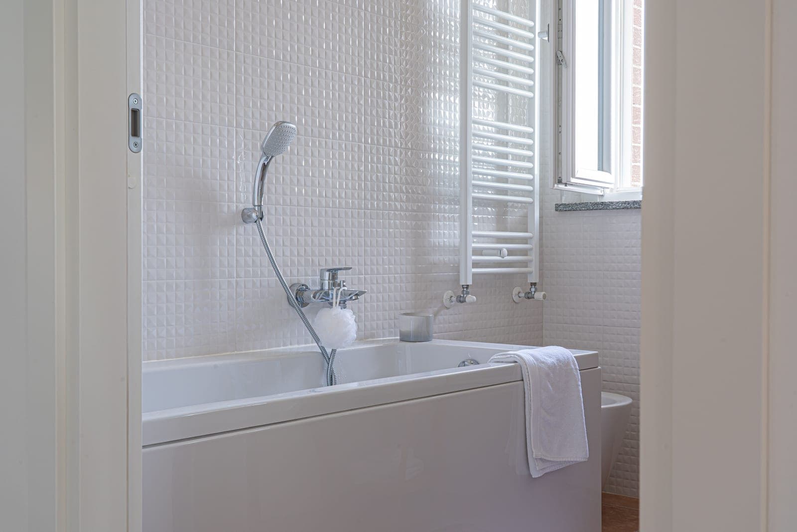 A bright bathroom with a bath towel beside a bathtub and shower