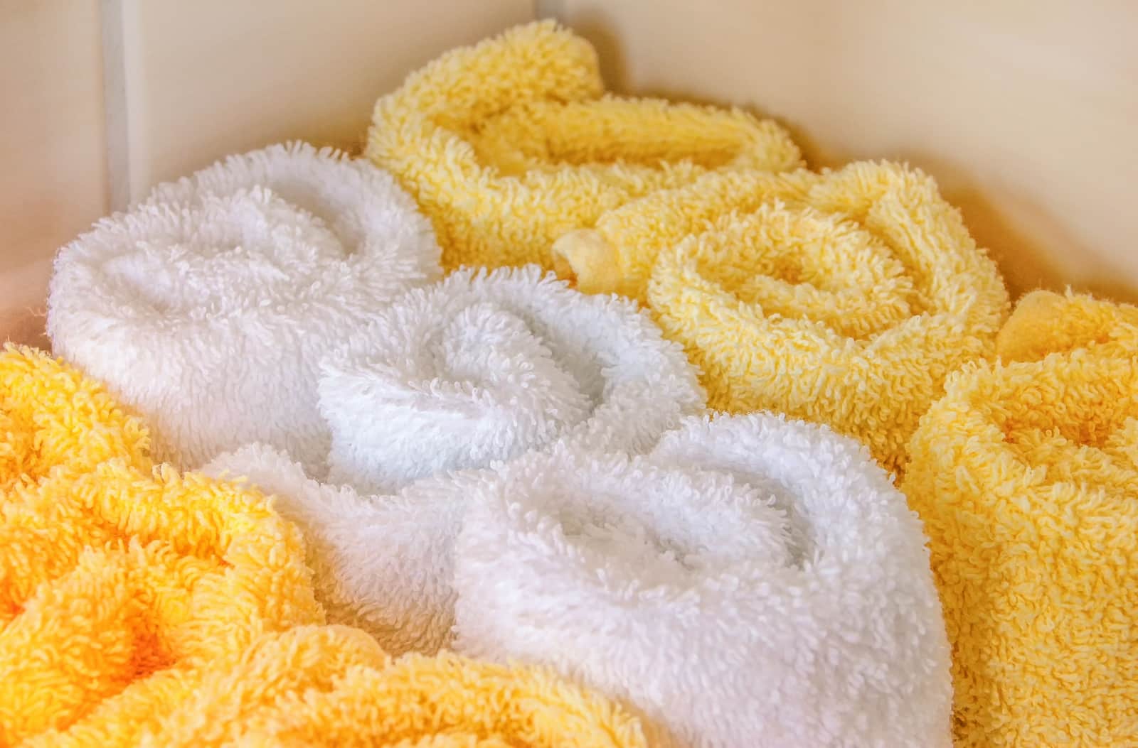 Rolled white towels arranged in a bright bathroom